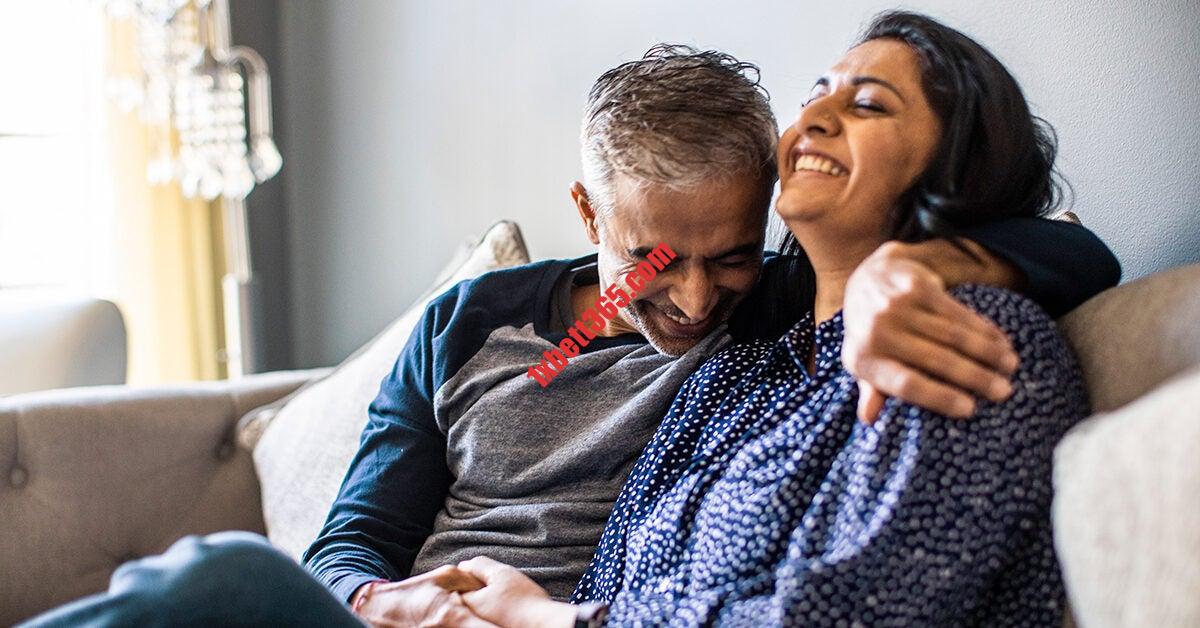 LGBT Dating During Covid | HER husband wife couple embracing on couch laughing smiling 1200x628 facebook 1200x628 1